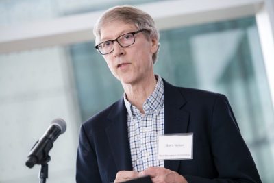 Researcher in navy jacket stands at microphone